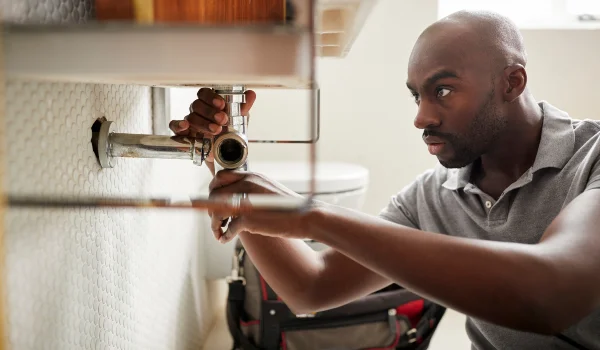 a male plumber fixing a bathroom faucet